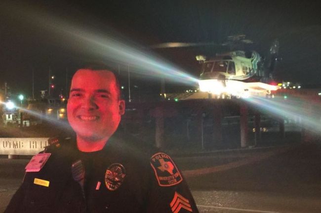 Office Rivera smiles as he stand in front of a helicopter on a pad at night.