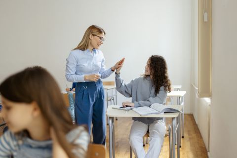 Student and teacher in classroom high fiving